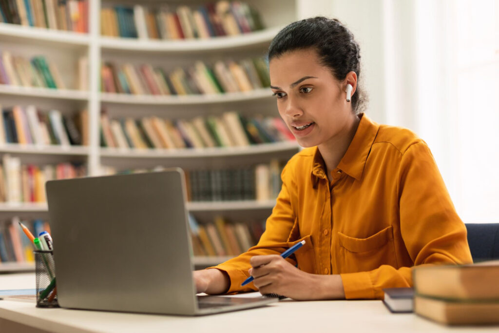 distance-education-concept-young-mixed-race-woman-sitting-desk-library-using-laptop-watching-lecture-webinar